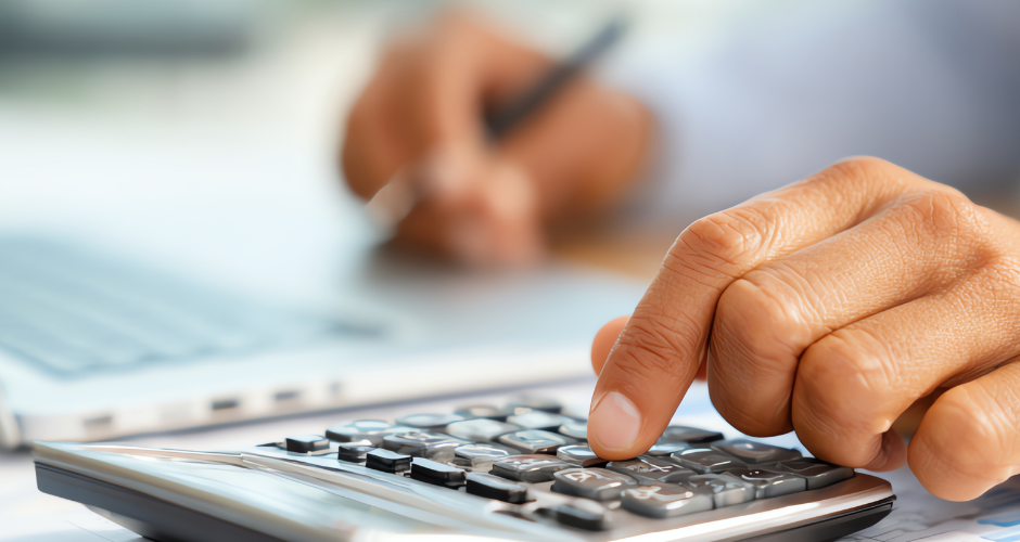 Close-up of a hand using a calculator during an insurance or rebuild cost calculation.