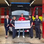 Brooklin Claims staff presenting a £790 charity cheque to firefighters at Bury Fire Station in front of a fire engine.